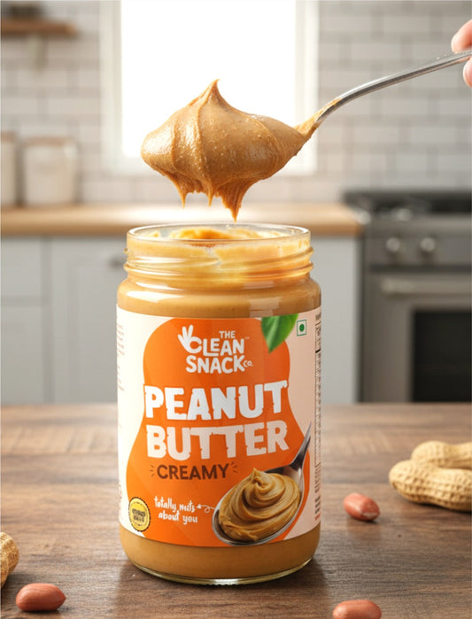 Jar of 'The Clean Snack' peanut butter with a spoonful being lifted, set against a kitchen background.